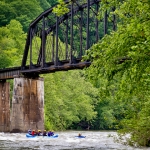 Rafters paddle beneath historic trestle