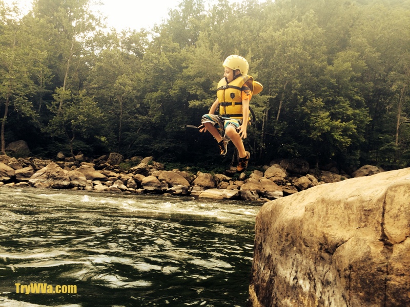A youth leaps into the New River