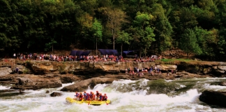 Rafters outfitted with River Expeditions watch raft-load plow through Sweets Falls on the Gauley River.