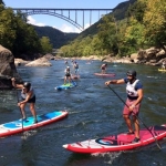 Racers on stand-up paddleboards ply the New River