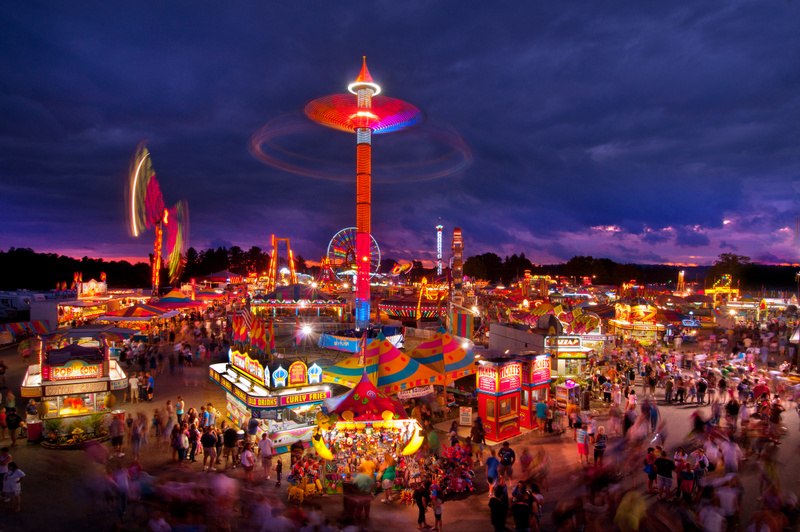 The midway at the State Fair of West Virginia rages with color at dusk at Fairlea, West Virginia.