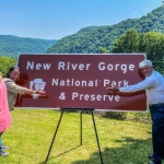 Sharon Cruikshank and Jack Scott, the mayors of Fayetteville and Hinton, celebrate the installation of signage designating the new New River Gorge National Park and Preserve in 2021.