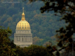 The gilded dome of the West Virginia Capitol stands out amid foliage at Charleston, West Virginia, in Kanawha County, in the Metro Valley Region.