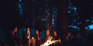 Campers gather around a fire in a West Virginia forest.