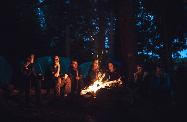 Campers gather around a fire in a West Virginia forest.