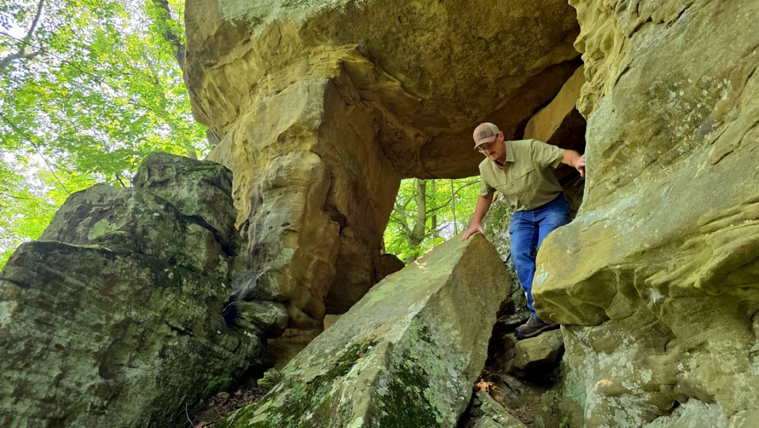 Wind Caves at Camp Kootaga: foundation member Tim Nolan climbs through a sandstone arch.