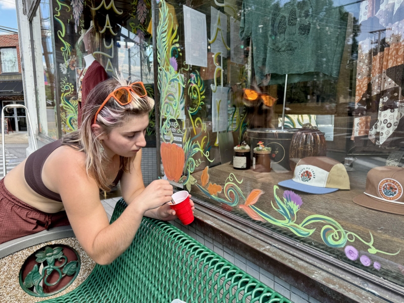 Fayetteville Creates: Kristin Carroll paints a storefront window in Fayetteville on the edge of the New River Gorge.