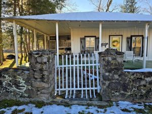 Historic cottage in 2025 includes rock wall, board-and-batten siding, wide porches, and screened porch.