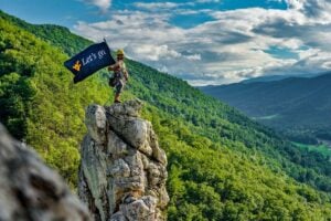 Paris Winfrey waves a WVU flag on top of Humphrey's Head at Seneca Rocks (WVU Photo)