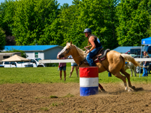 A rider rounds a barrel during competition at the Alderson Horse Show, an equestrian tradition associated with the Alderson Fourth of July celebration. The event returns to the historic Pence Springs resort grounds, where horseback riding was once among the resort's most popular attractions.