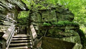 A stairway along Beartown State Park's boardwalk passes between massive sandstone boulders, offering visitors an intimate view of the natural stone labyrinth.