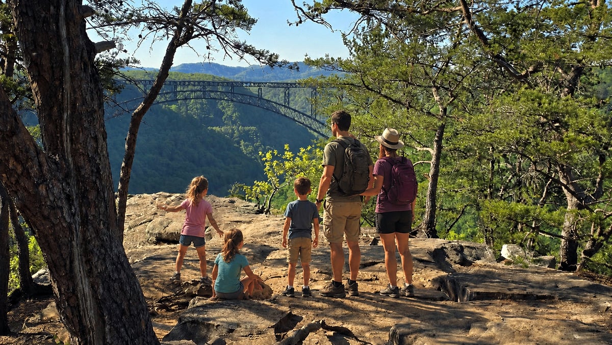 A family overlooks the New River Gorge Bridge from Long Point Trail in the New River Gorge National Park and Preserve near Fayetteville. The overlook is among West Virginia's most popular destinations for travelers exploring the Mountain State by road trip. (Photo: David Sibray)