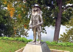 The stainless-steel statue of frontier heroine Anne Bailey at Tu-Endie-Wei State Park in Point Pleasant was created by Mason County sculptor Bob Roach as part of a series honoring figures associated with the region's frontier history. Bailey, remembered for her courage and exploits along the Virginia and West Virginia frontier, is depicted carrying a rifle and wearing traditional frontier attire.