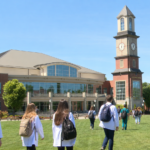 Medical students, including several wearing white lab coats, walk across the campus of the West Virginia School of Osteopathic Medicine in Lewisburg. The medical school is West Virginia's largest and leads the state in producing physicians who remain in West Virginia, practice primary care, and serve rural communities.