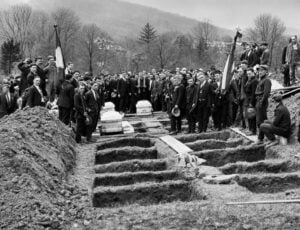 Mourners gather around rows of freshly dug graves during a mass funeral following the Benwood Mine Disaster of April 28, 1924. An explosion at the Benwood Mine in Marshall County killed 119 miners, making it one of the deadliest mining disasters in West Virginia history.