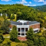 An aerial view of the historic Pence Springs Hotel in Summers County, W.Va., shows the former mineral springs resort surrounded by the forests and rolling hills that made it one of Appalachia's best-known mountain retreats. The 138-acre property is now being offered for sale through Foxfire Realty.