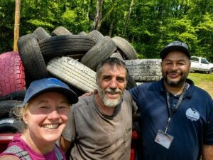 Community members Krissy Stiver and Wayne Ramsey join Fayette County Litter Control Officer Dan Helton in front of a truckload of discarded tires collected during a community cleanup in Winona, W.Va. The effort removed nearly 7.7 tons of trash from the former coal town, reflecting a growing commitment among residents to restore and reinvest in their community.