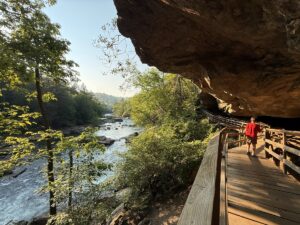 A hiker follows the boardwalk beneath the Alum Cave rock overhang along the Middle Fork River at Audra State Park. The photograph won the outdoor recreation category. (Photo by Stasha Ray)