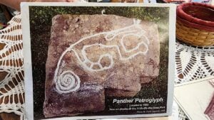 An older photograph shows the interpreted lines of the Water Panther petroglyph highlighted for visibility. The prehistoric stone carving is now preserved at Tu-Endie-Wei State Park in Point Pleasant, W.Va.