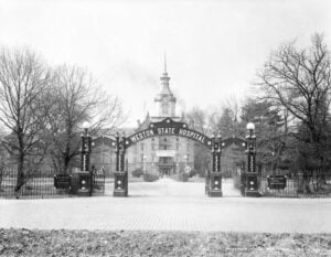 The entrance to Weston State Hospital frames the landmark sandstone hospital in Weston, West Virginia. The institution opened in 1864 as the West Virginia Hospital for the Insane and was renamed Weston State Hospital in 1913. (West Virginia and Regional History Center, WVU Libraries)