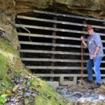 West Virginia Explorer publisher David Sibray stands beside a bat-friendly gate at an abandoned mine portal in the Piney Creek Gorge near the New River Gorge in southern West Virginia. Such gates allow bats to enter abandoned mine workings while restricting human access.