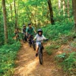 Mountain bikers ride a wooded trail in Beckley, West Virginia, where an expanding trail network is part of an effort to develop the city as an outdoor recreation destination.