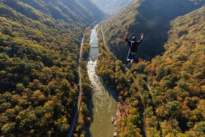 A BASE jumper leaps into the New River Gorge during Bridge Day as autumn colors spread across the gorge in southern West Virginia. The annual October event draws visitors to the New River Gorge Bridge and surrounding communities. (Photo courtesy Bridge Day)