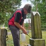 Gary Morefield cleans the grave marker of Clarkson Prince in Raleigh County, West Virginia. Morefield joined an effort to clean and document the historic cemetery and the graves of families who settled the area.