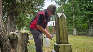 Gary Morefield cleans the grave marker of Clarkson Prince in Raleigh County, West Virginia. Morefield joined an effort to clean and document the historic cemetery and the graves of families who settled the area.