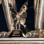 A miniature replica of the Mothman stands at the feet of the original stainless-steel statue created by Bob Roach in Point Pleasant, West Virginia. Roach’s daughter, Kelly Roach Miller, has helped preserve the story behind her father’s famous sculpture.