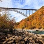 The New River Gorge Bridge rises above the New River amid autumn foliage in southern West Virginia. Fall brings cooler weather, whitewater recreation and changing colors to the national park region.