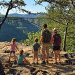 New River Gorge Bridge spanning a deep, forested canyon, viewed from the rocky Long Point overlook in West Virginia.